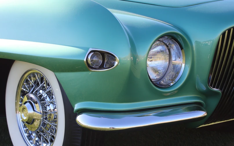 a close up of a mint green car with chrome rims