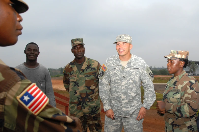 a group of soldiers are talking while one guy is wearing a hat