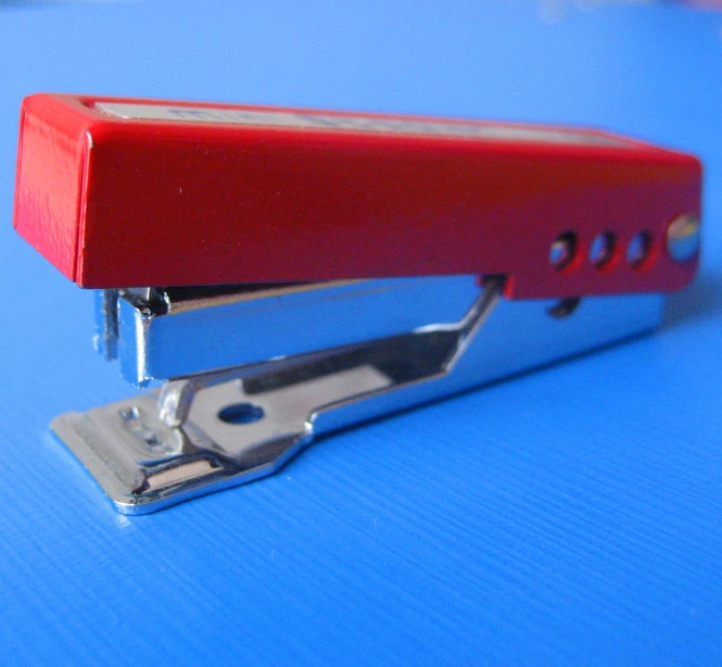 a stapler sitting on top of blue table with a red handle