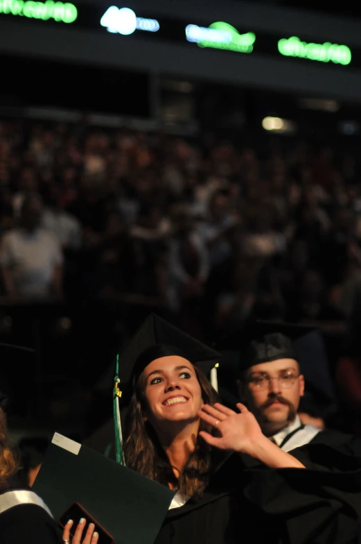 a woman in a graduation gown and a man in a cap at the podium