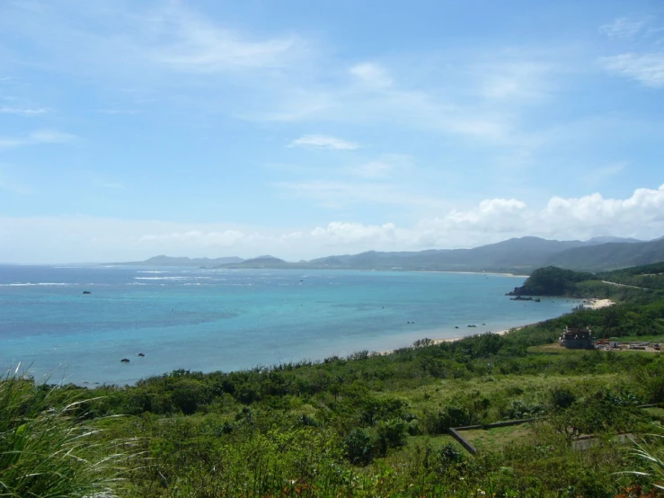 a blue ocean sits with lush green vegetation on the far side