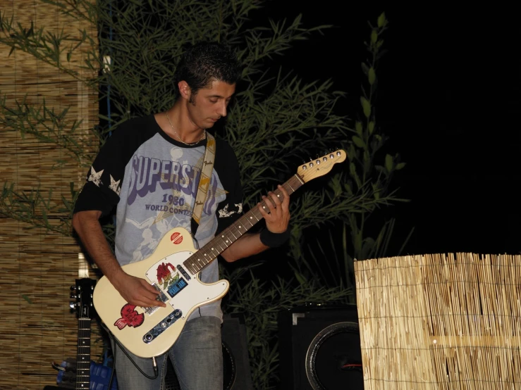 a man playing the guitar by a wall