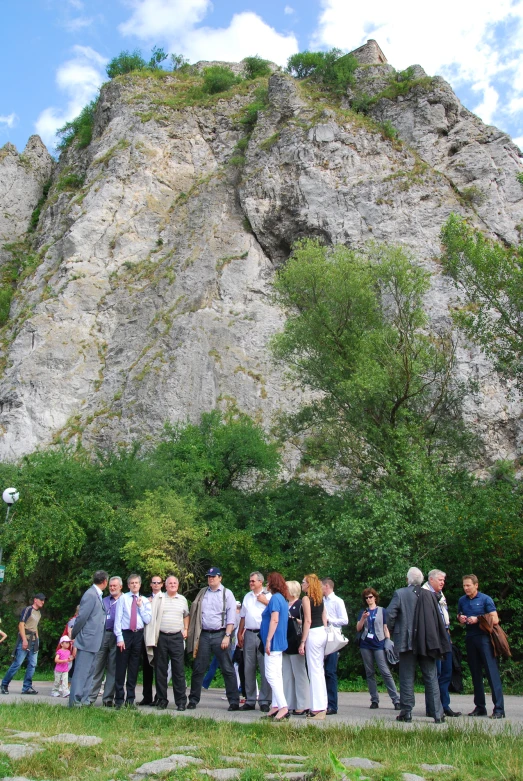 a large group of people standing around in front of a rocky area