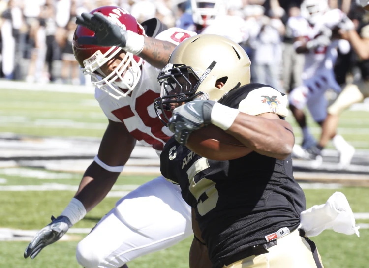 two football players collide while each of them is trying to block out an opposing football player