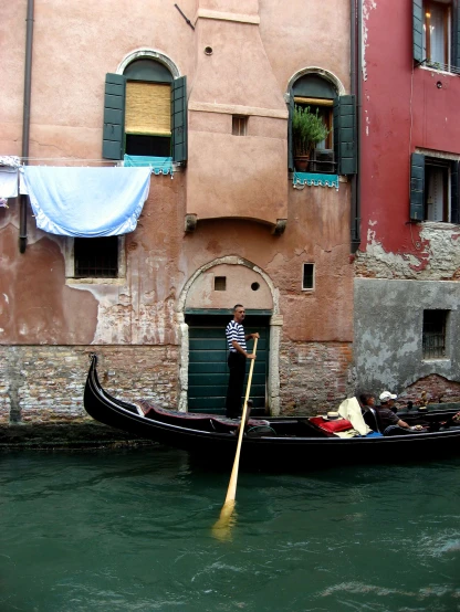 the man in his gondola paddles a boat down the canal