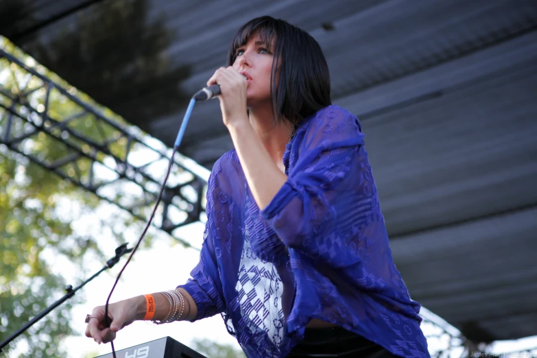 a woman is standing at the stage and holding up her microphone