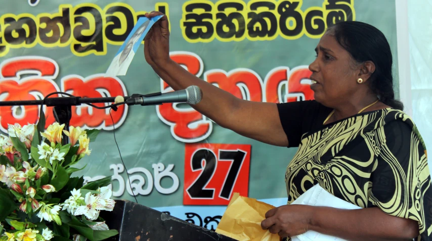 a woman is reading a paper in front of a microphone