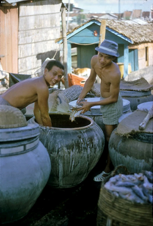 two men are washing their hands in a bucket