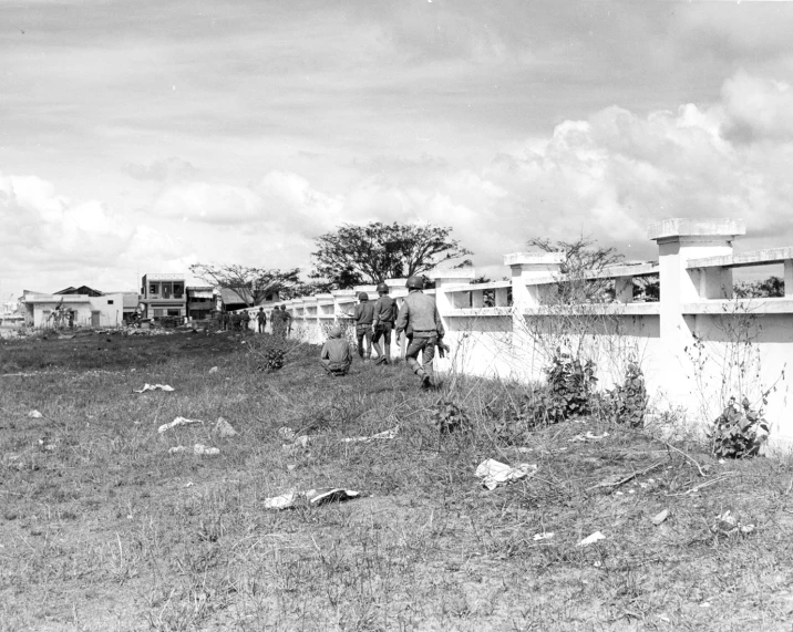 two people are walking in the grass towards buildings