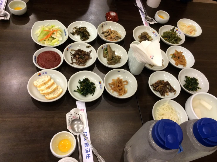 several bowls of food on a table with forks and spoons