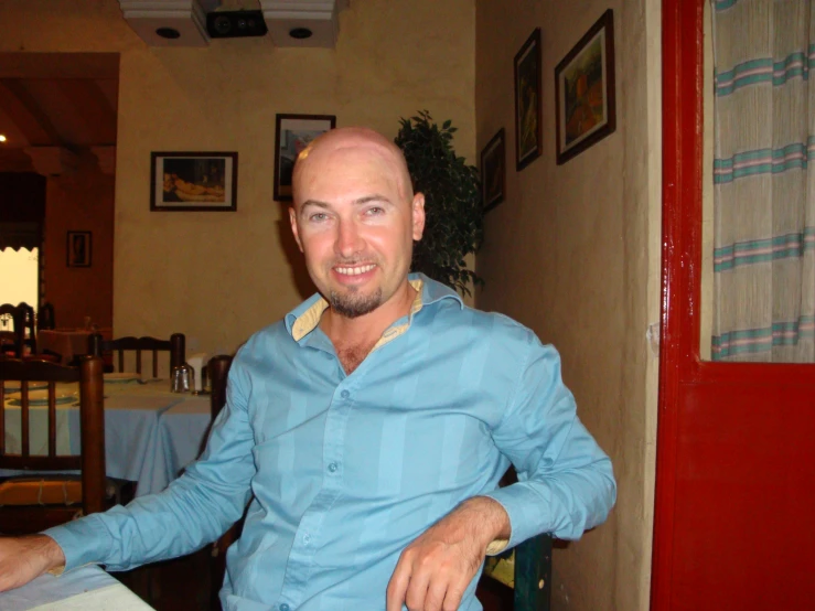 a smiling man sitting at a table at a restaurant