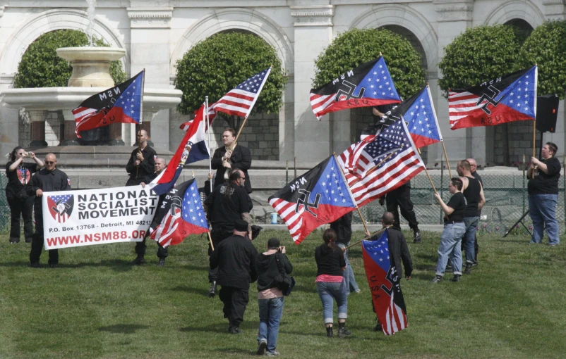 several people in front of a white building with many american flags