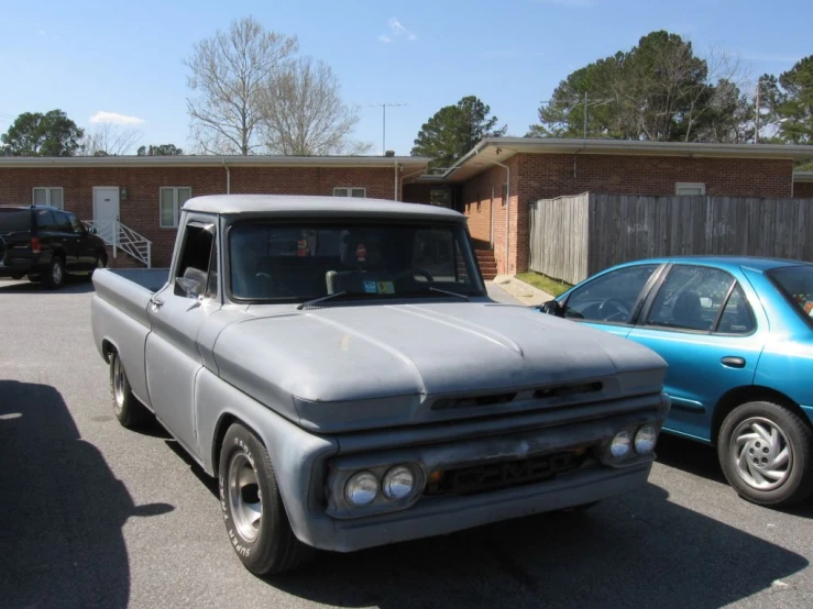 a parked grey truck next to a blue car