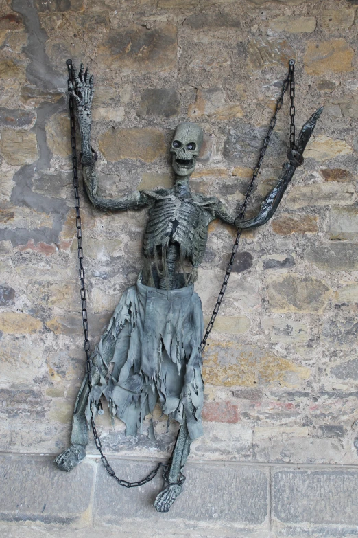 a statue of a skeleton hanging from chains