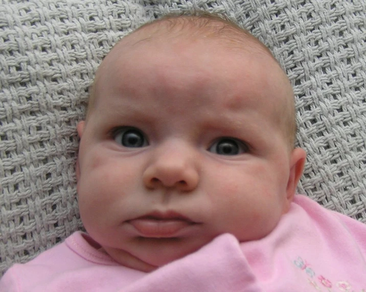 a baby with big eyes has pink dress on