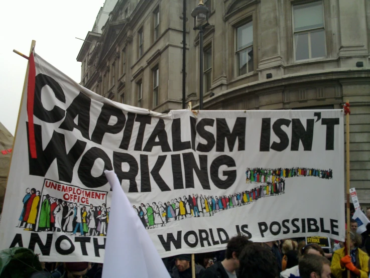 a group of protesters holding a sign that says capitalism isn't working