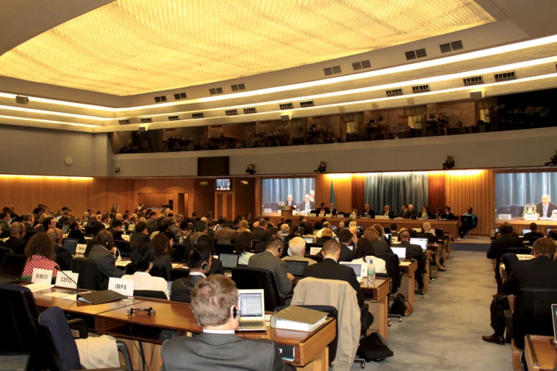 a meeting room with many people at desks