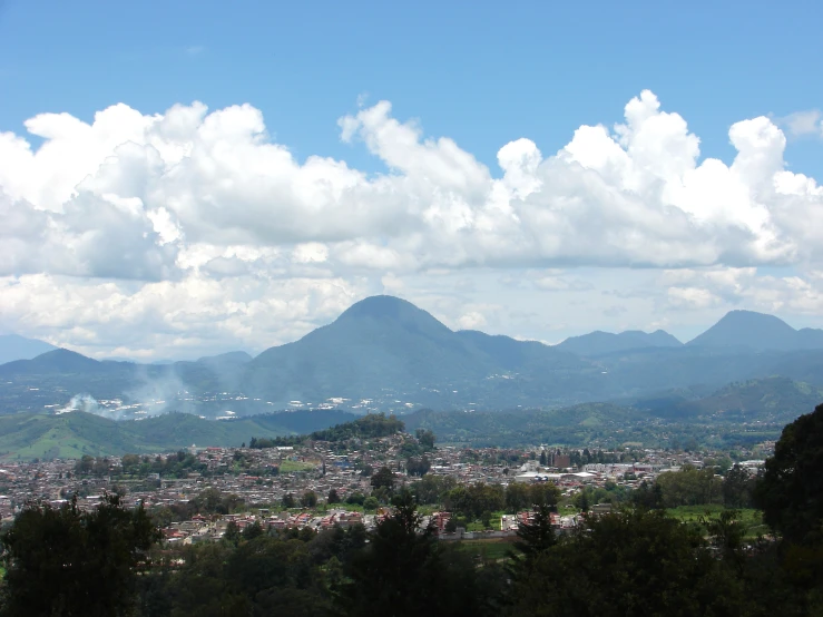 the view of some mountains in the distance with clouds overhead