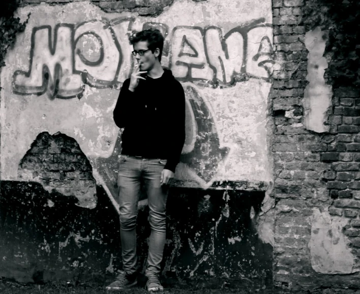 a man is smoking in front of a graffiti wall