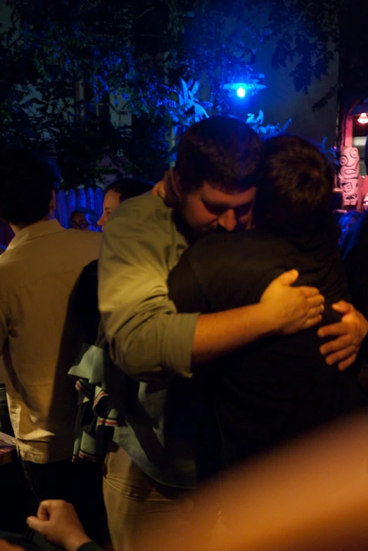 there are two people hugging each other in front of a crowd