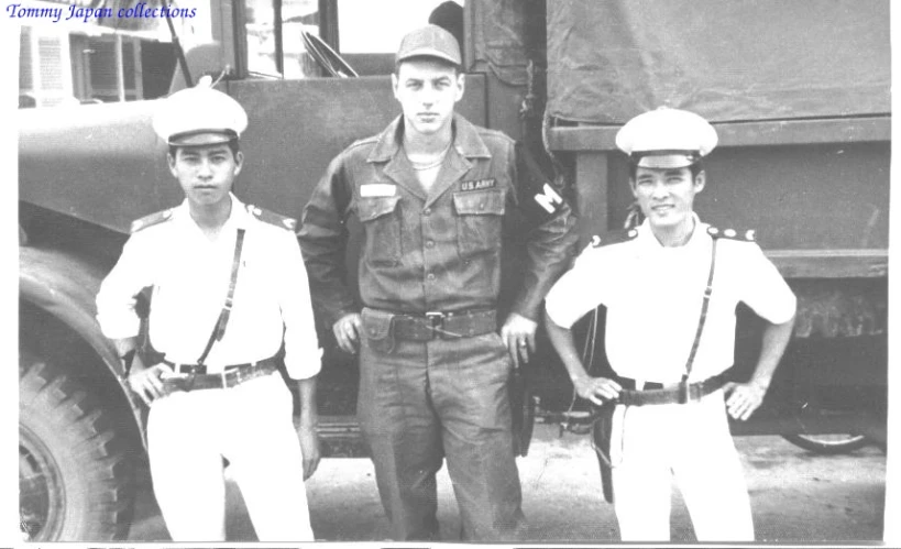 three people in military uniforms standing next to a large truck