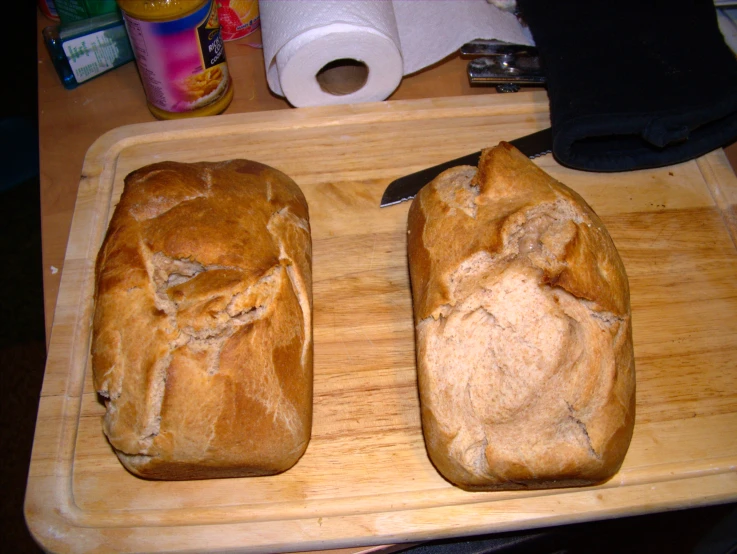 two loaves of bread on a wooden  board