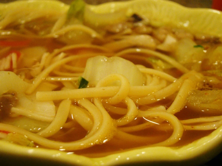 a bowl of chinese noodle soup with some lemon wedges