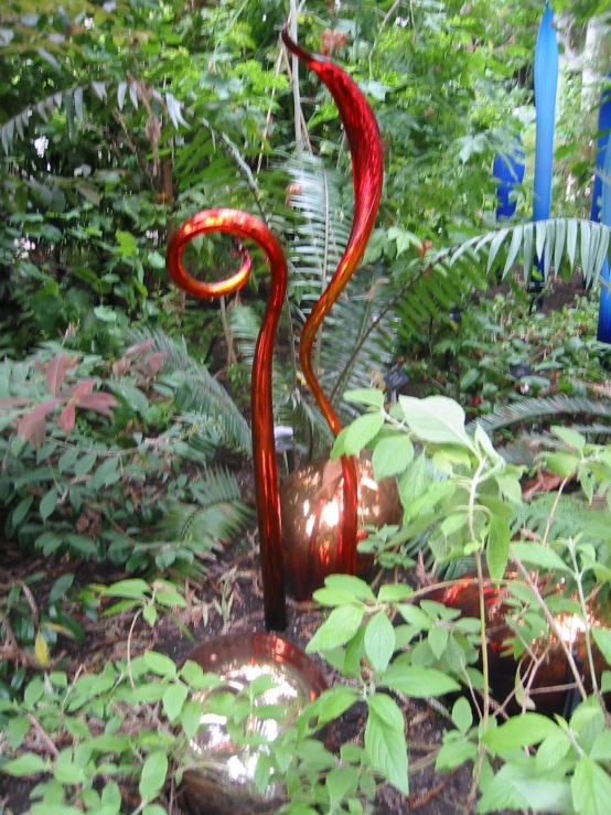 a metal sculpture in the grass surrounded by trees and vegetation