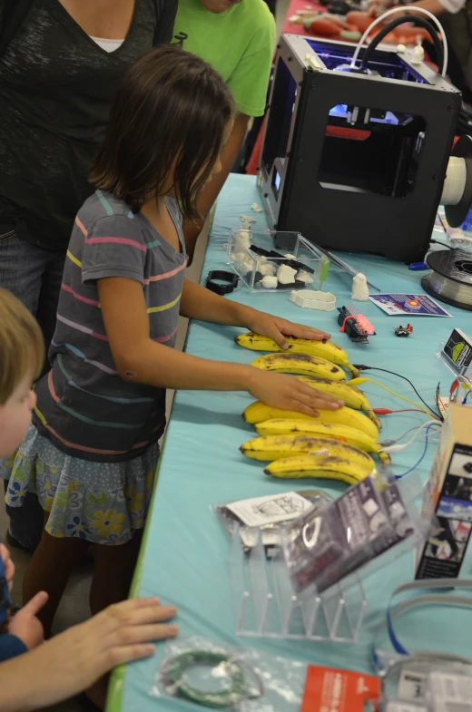 two girls standing near a table with bananas on it