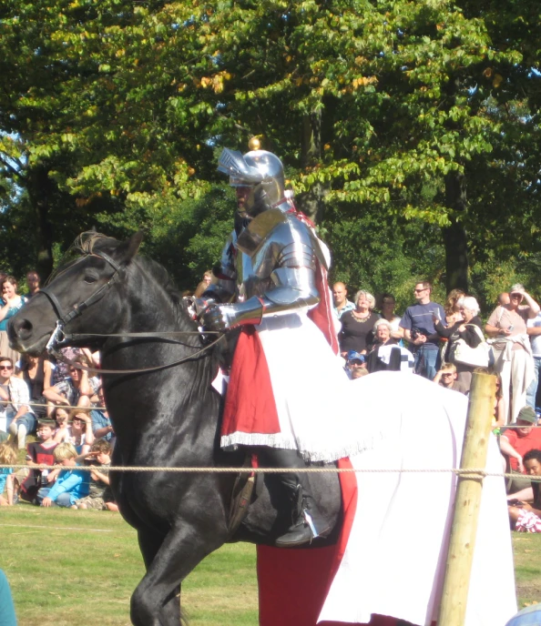 a man in armor riding on a horse near spectators