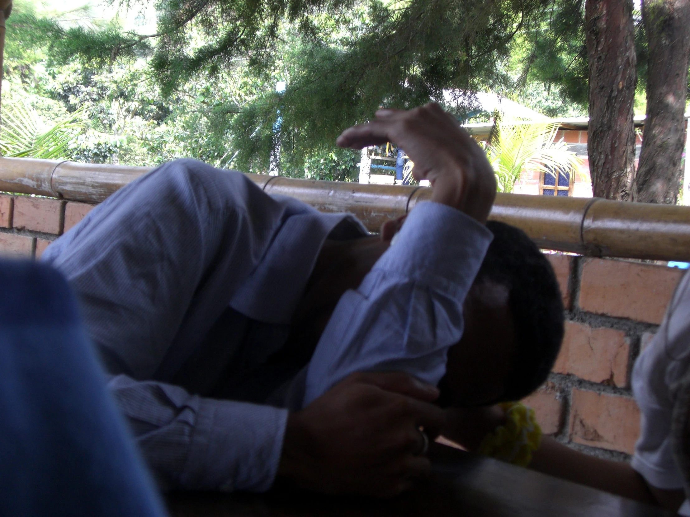 a young man laying on a bench reaching up to grab soing