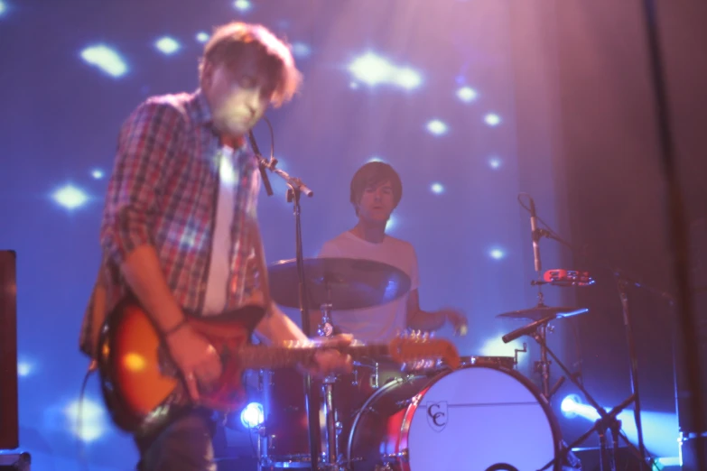 two guys are playing together on stage while the singer is on the microphone