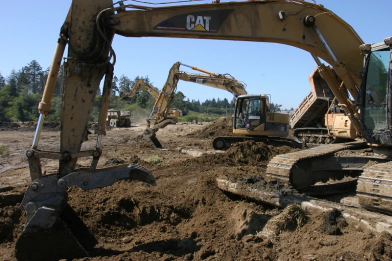 several machines dig dirt out of the ground