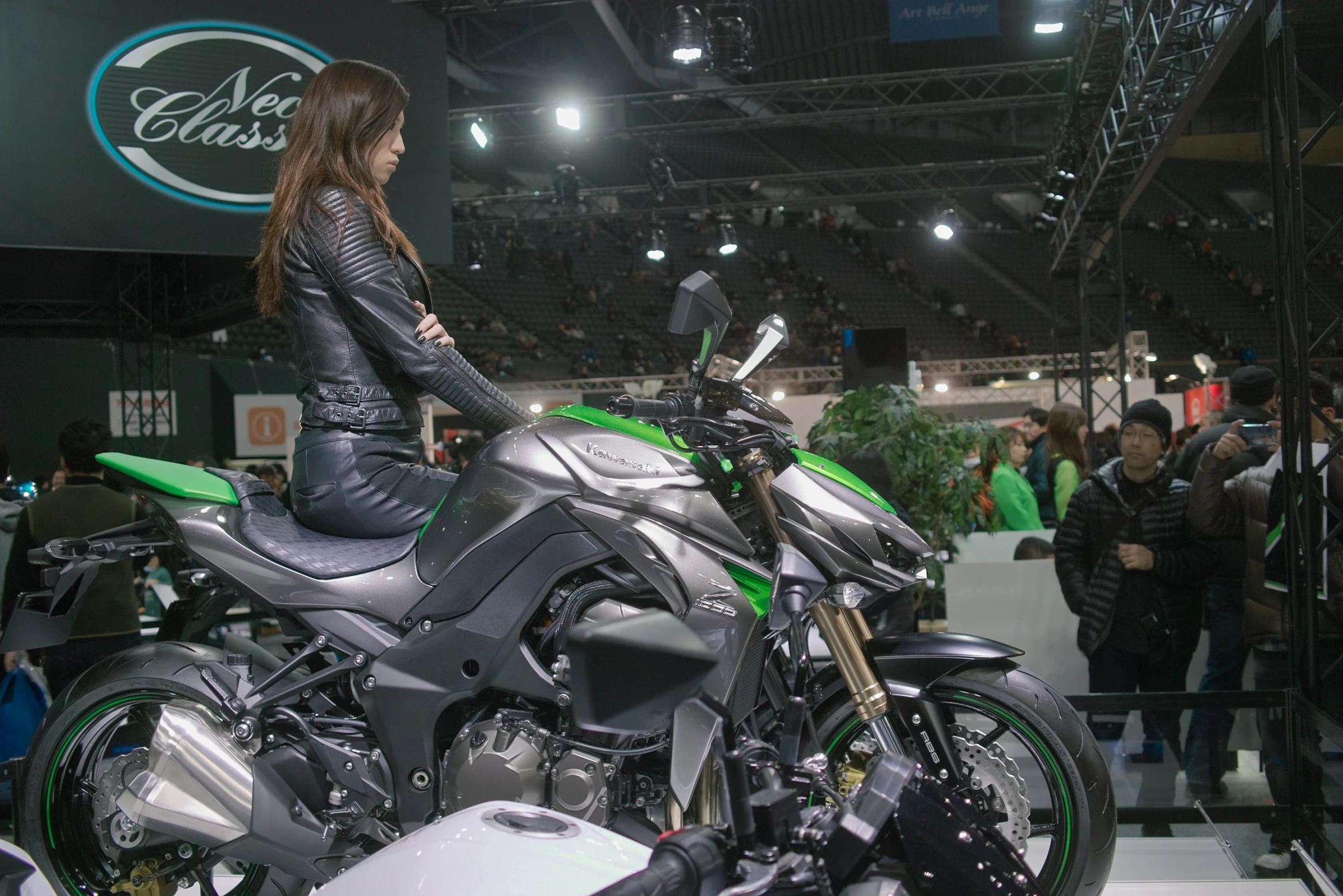 the woman is sitting on her green and black motorcycle