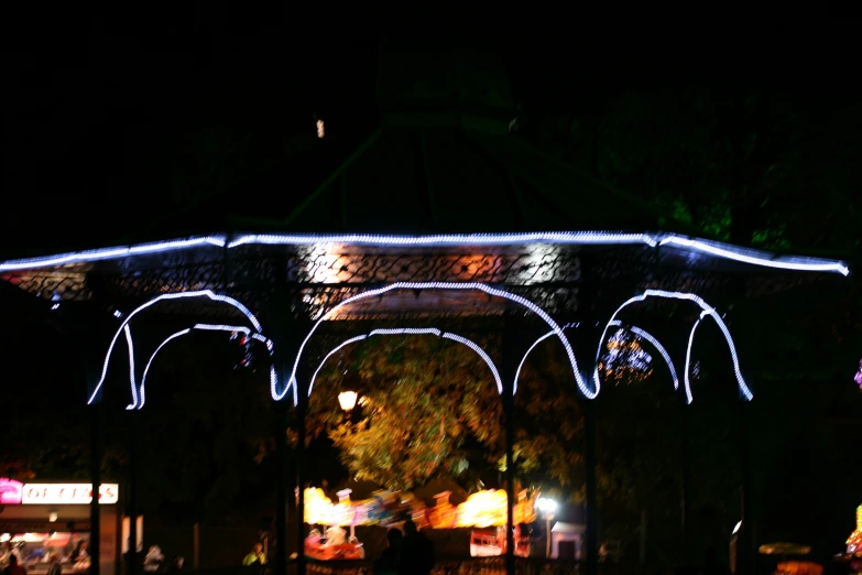 a nighttime scene with an illuminated structure, with people and trees