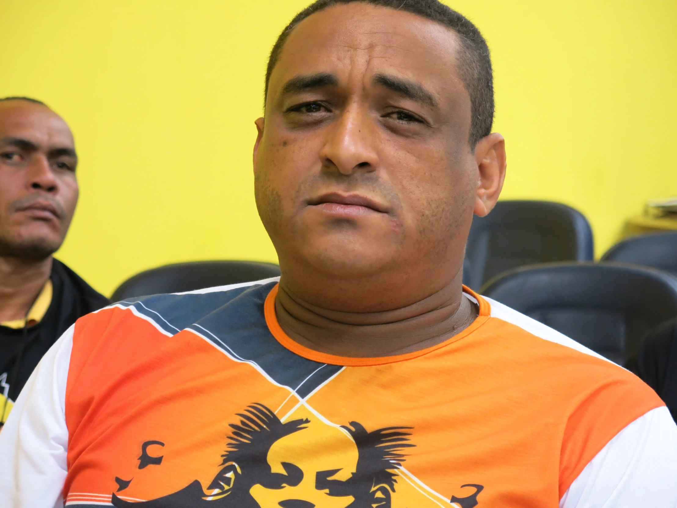 a man wearing an orange shirt is staring at the camera