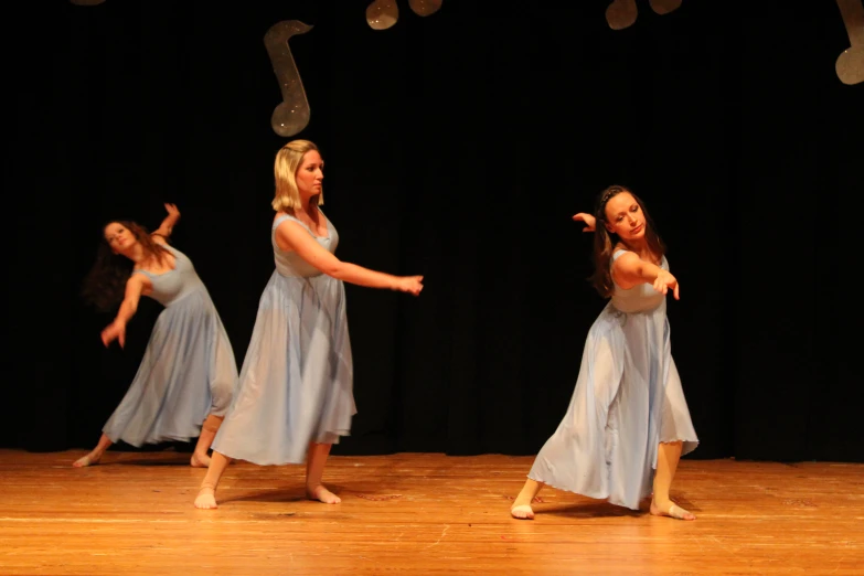 a group of girls dressed in dresses performing on stage