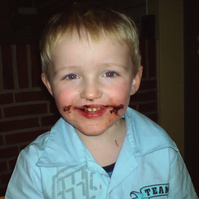 a small child is wearing chocolate while smiling