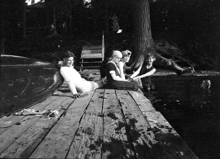 a woman sitting on a dock next to two boys