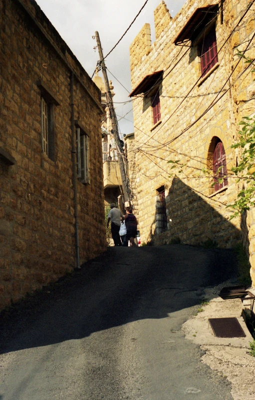 two people on their motorcycles standing near the side of a building