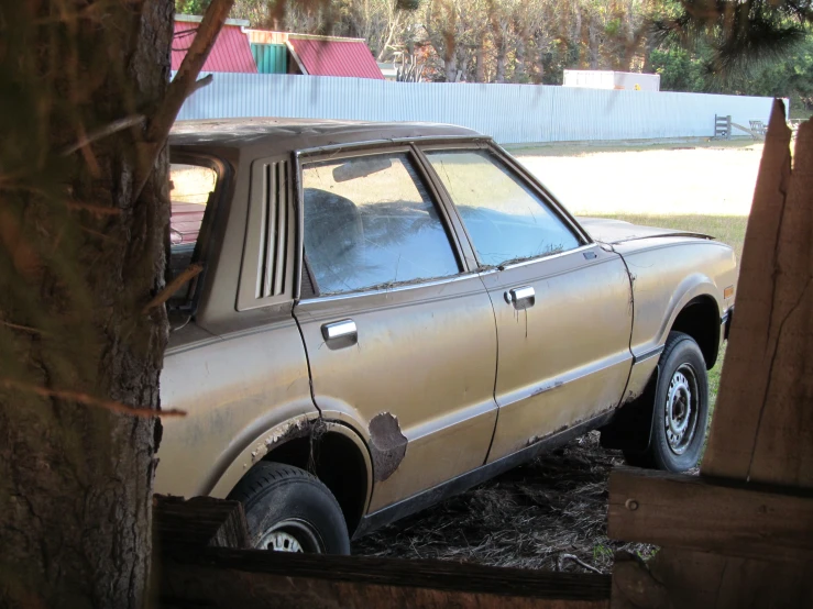 a car is in the dirt parked next to a tree