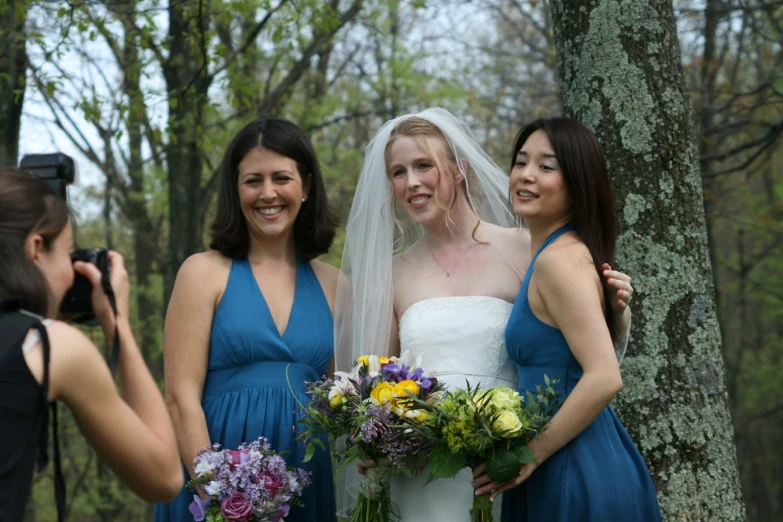 a bride and three girls standing in front of a tree