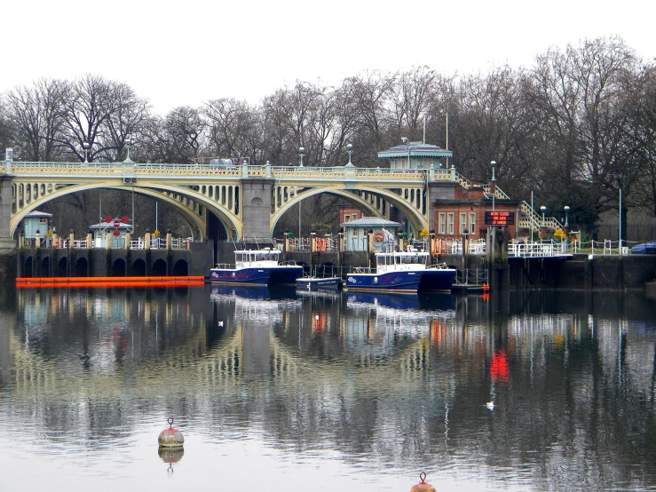 there are many boats on the water under an old bridge