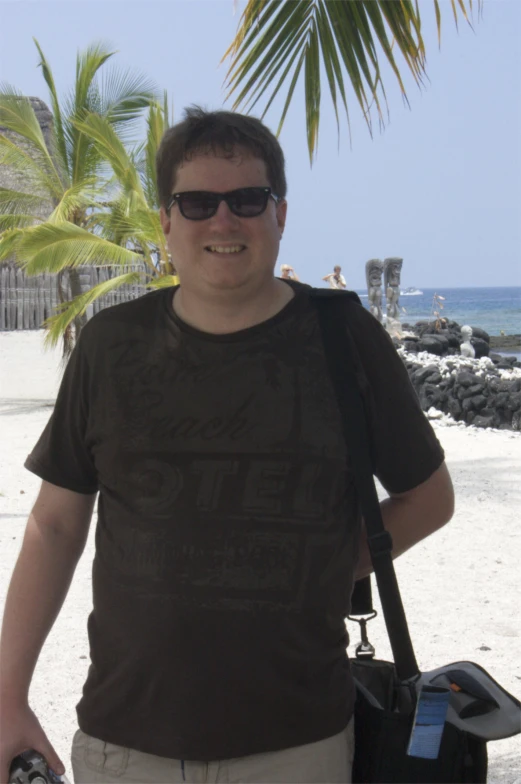 a man standing on a beach with a cell phone in his hand