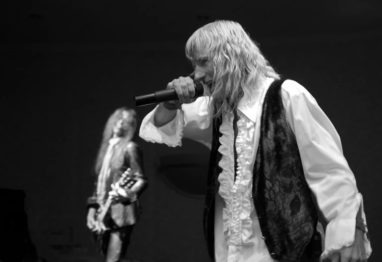 a male singer and a female guitarist with long blonde hair on stage