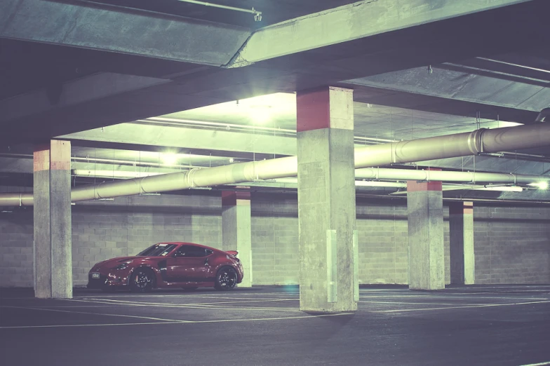 the small red car is parked in the parking garage