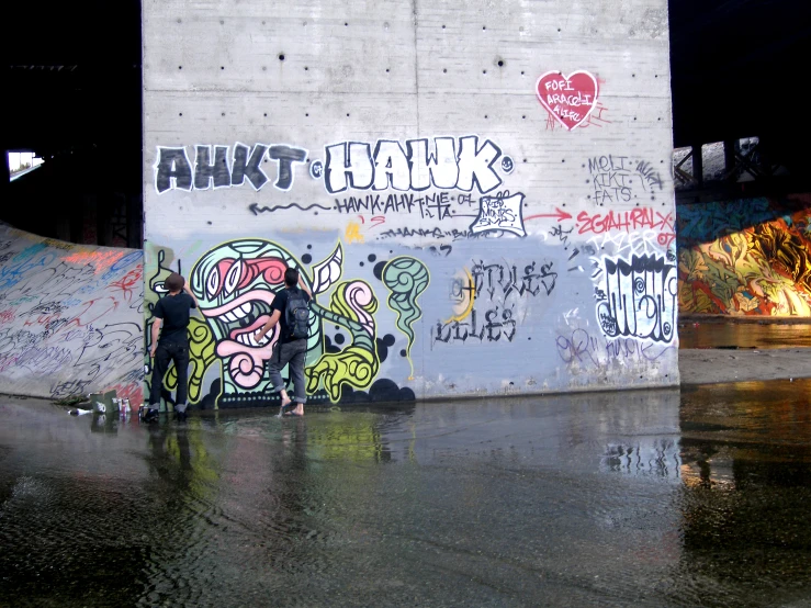 two people in front of a large piece of graffiti