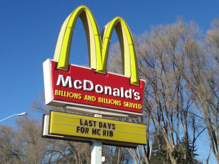 the sign for a mcdonald's restaurant with trees in the background