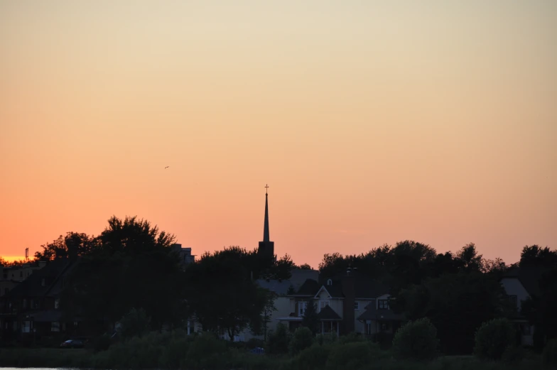 a city skyline with buildings and trees silhouetted by the sunset