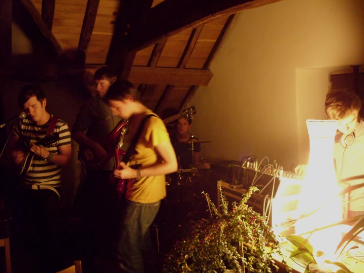 the man in yellow shirt is playing his guitar and other people are on the floor